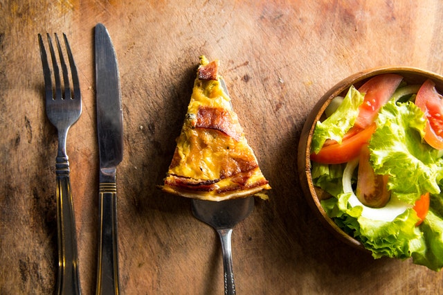 A slice of frittata or quiche next to a chopped salad