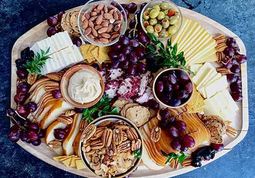 Vegetarian cheese platter with sliced cheese, pears, nuts, hummus and olives.