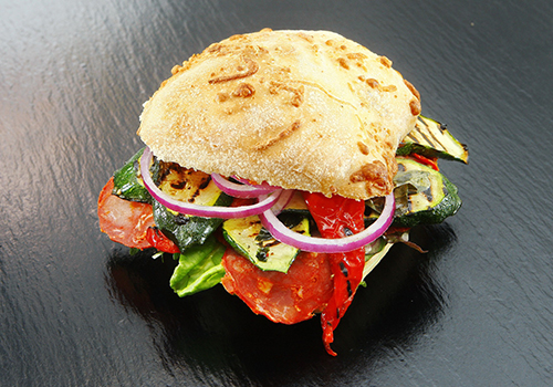 Ciabatta bun with grilled vegetables, fresh raw red onion, lettuce and hot salami.