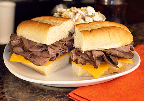 Long hoagie roll with roast beef and sliced cheese.