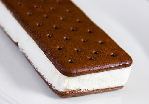 A close up of a vanilla ice cream sandwich with chocolate biscuits.