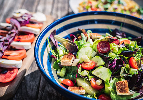 A leafy green salad with tomatoes, croutons and spring onions.